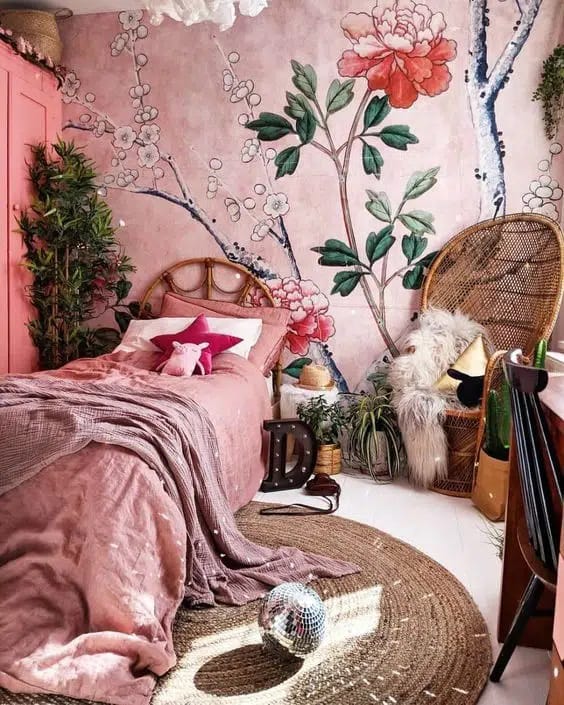 A bedroom with a pink floral mural, rattan furniture, and boho decor elements.