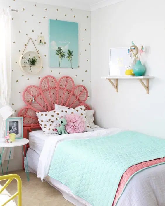 A bedroom with pastel colors, a pink rattan headboard, and a polka dot wall pattern.