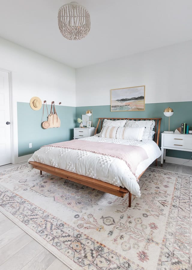 A minimalist bedroom with a calming green and white color palette, featuring natural wood elements.