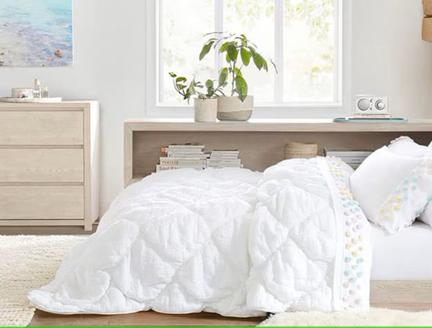 A tranquil teen bedroom with white bedding, light wood furniture, and a large window letting in natural light.