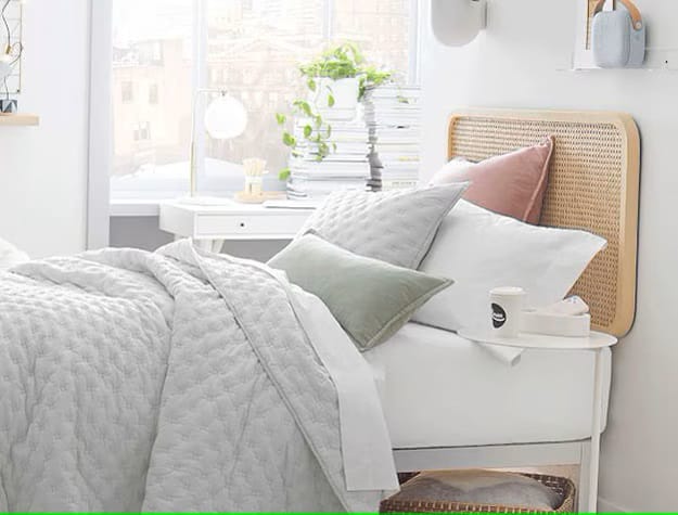 A bright teen bedroom with natural light, green plants, and light-colored furniture.