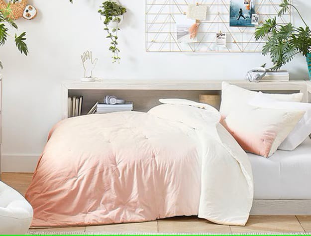 A cozy teen bedroom with neutral-toned bedding, plush pillows, and simple decor.