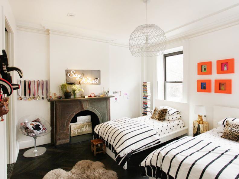 Monochrome shared teen bedroom with striped bedding, minimalistic decor, and colorful artwork.