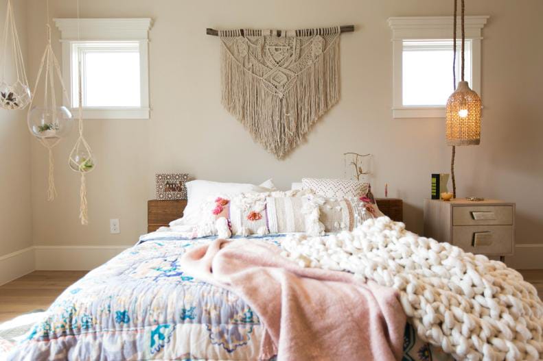 Boho-style teen bedroom with colorful bedding, macramé wall hanging, and hanging planters.