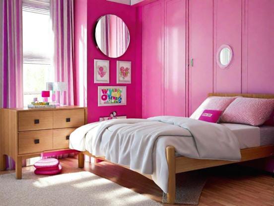 A bedroom with bold pink walls and wardrobes, complemented by light wood furniture.