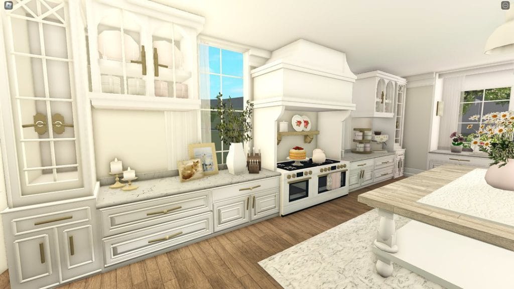 A bright and elegant Bloxburg kitchen with white cabinetry, marble countertops, and gold hardware.