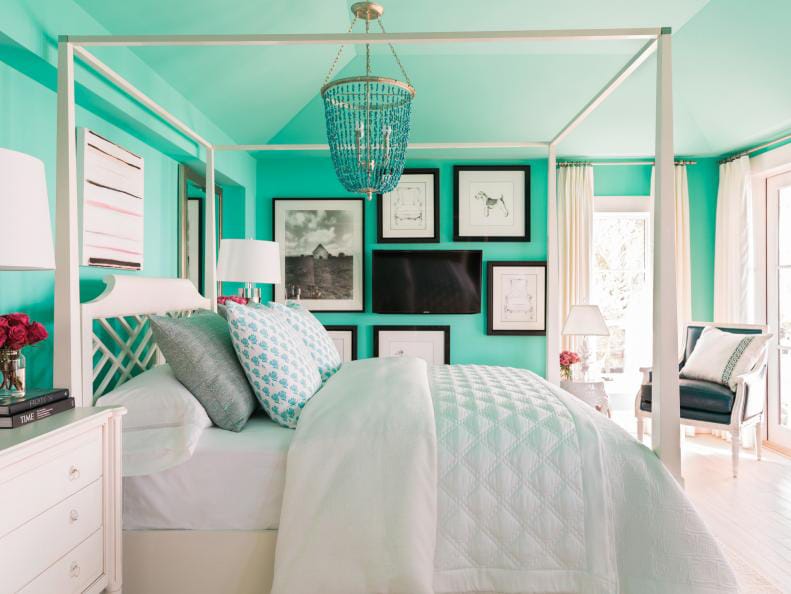 Bright turquoise teen bedroom with a white canopy bed, statement chandelier, and framed artwork.