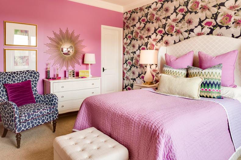 Teen bedroom with bright pink walls, floral accent wall, and a stylish armchair.