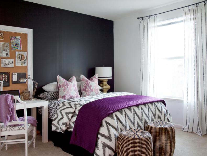 Modern teen bedroom with a black accent wall, purple bedding, and geometric patterns.