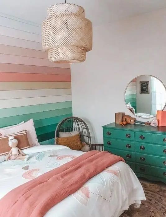 Teen bedroom with a rainbow-striped accent wall and a green dresser.