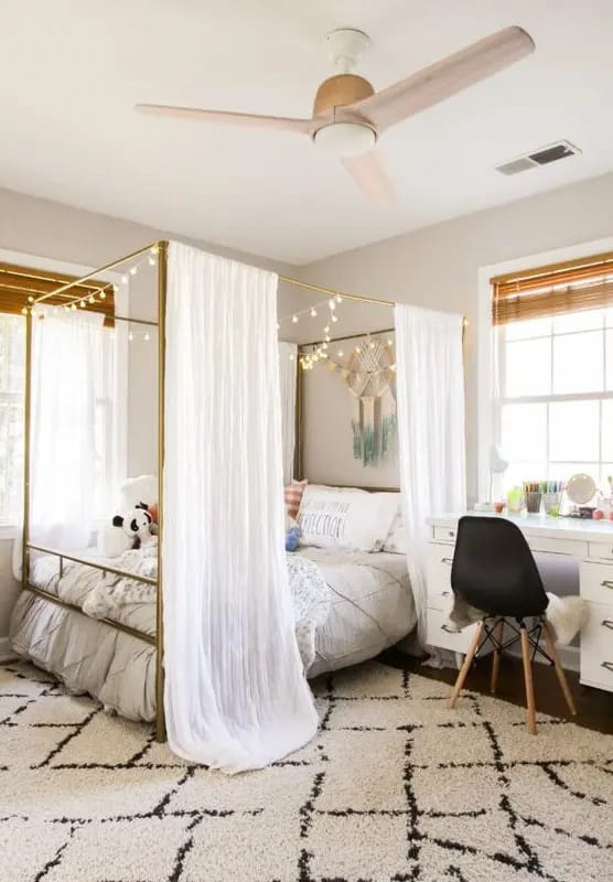 Teen bedroom with a canopy bed, white curtains, and fairy lights.