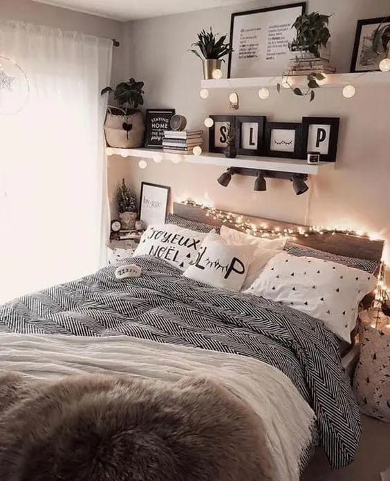 Bedroom with cozy string lights draped over a bed with fluffy blankets and decorative pillows.