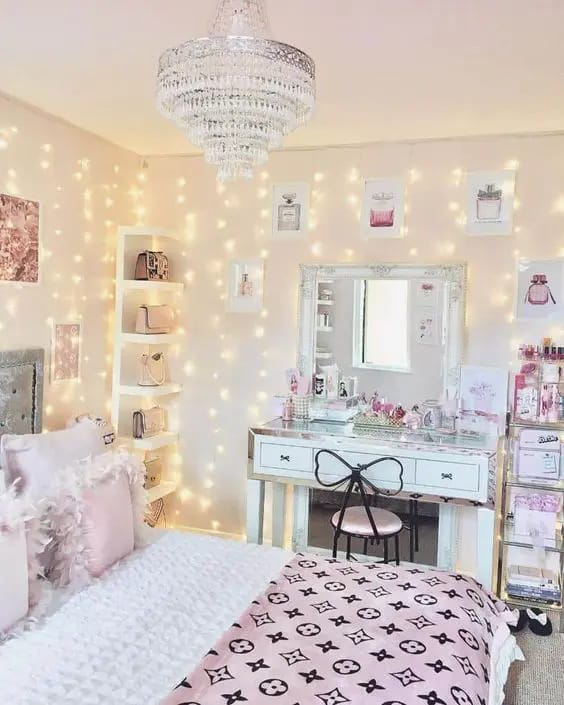 Glamorous bedroom with a chandelier, string lights, and a vanity table in a pink and white color scheme.