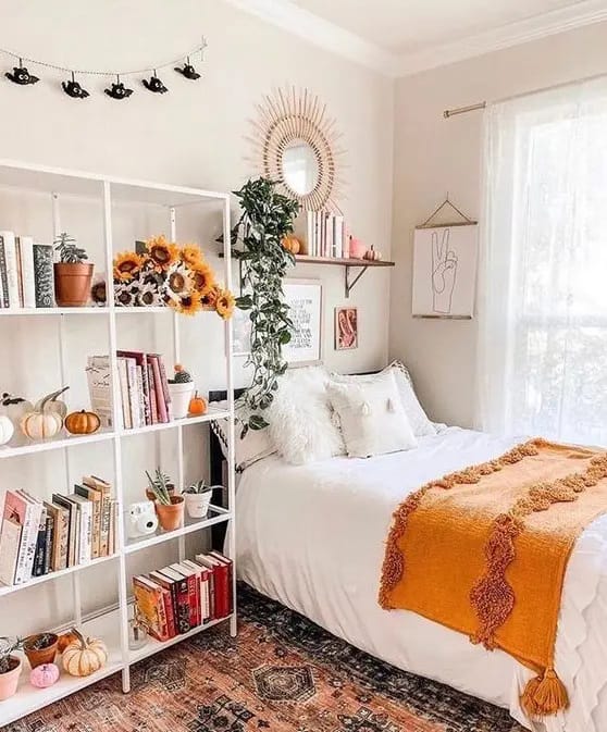 Teen bedroom with orange autumn accents, open bookshelf, and natural sunlight.