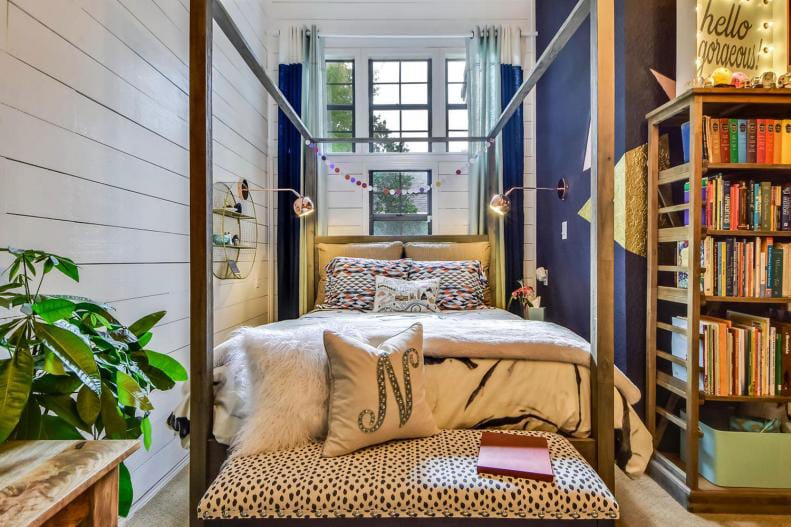 Cozy teen bedroom with a four-poster bed, dark curtains, bookshelf, and plush bedding.