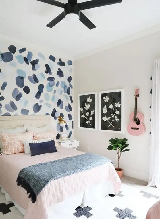 Artistic teen bedroom with painted accent wall, pink guitar, and cozy bedding.