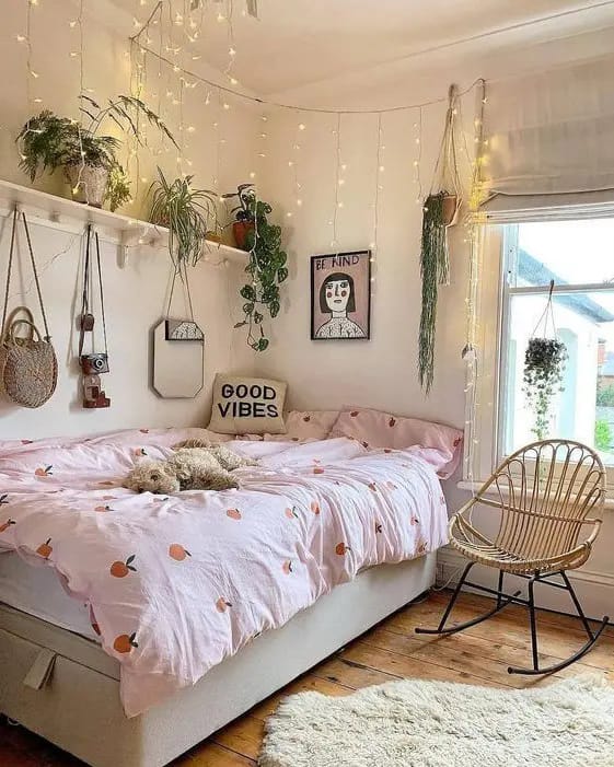 Boho-inspired room with hanging plants, string lights, and a peach-patterned duvet.