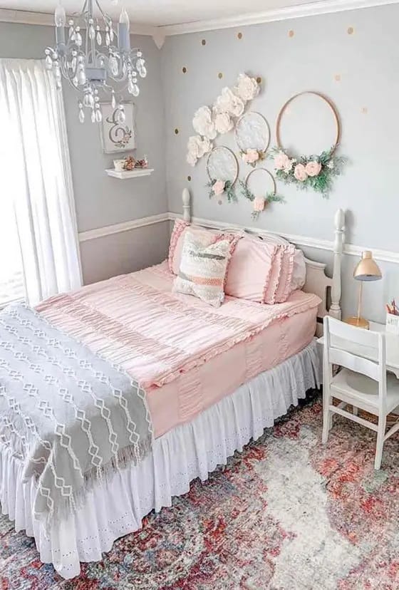 Feminine room with floral wall decor, pink bedding, and a chandelier.