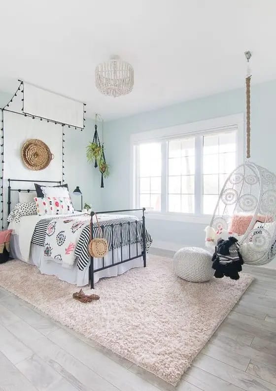 Playful design with a hanging chair, colorful bedding, and a mix of patterns.