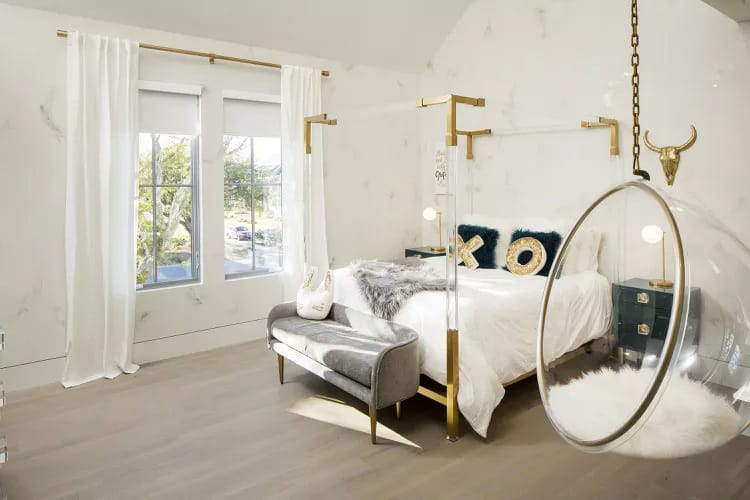 Modern room with gold accents, a hanging chair, and luxurious decor.