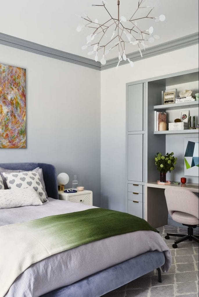 Cozy bedroom with a gradient bedspread, modern artwork, and a minimalist study nook.