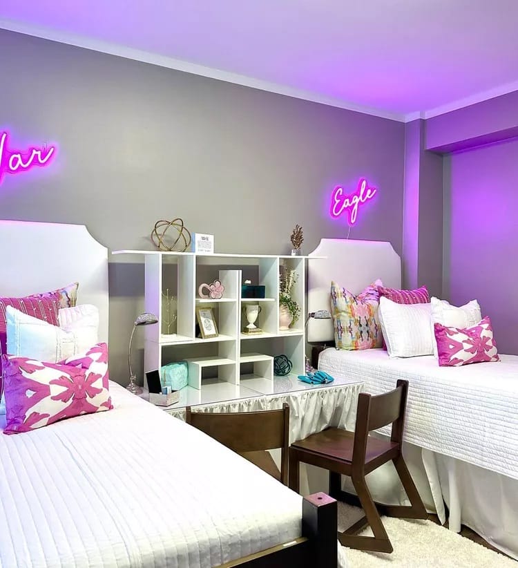 Modern dorm room with twin beds, white linens, and neon name signs.