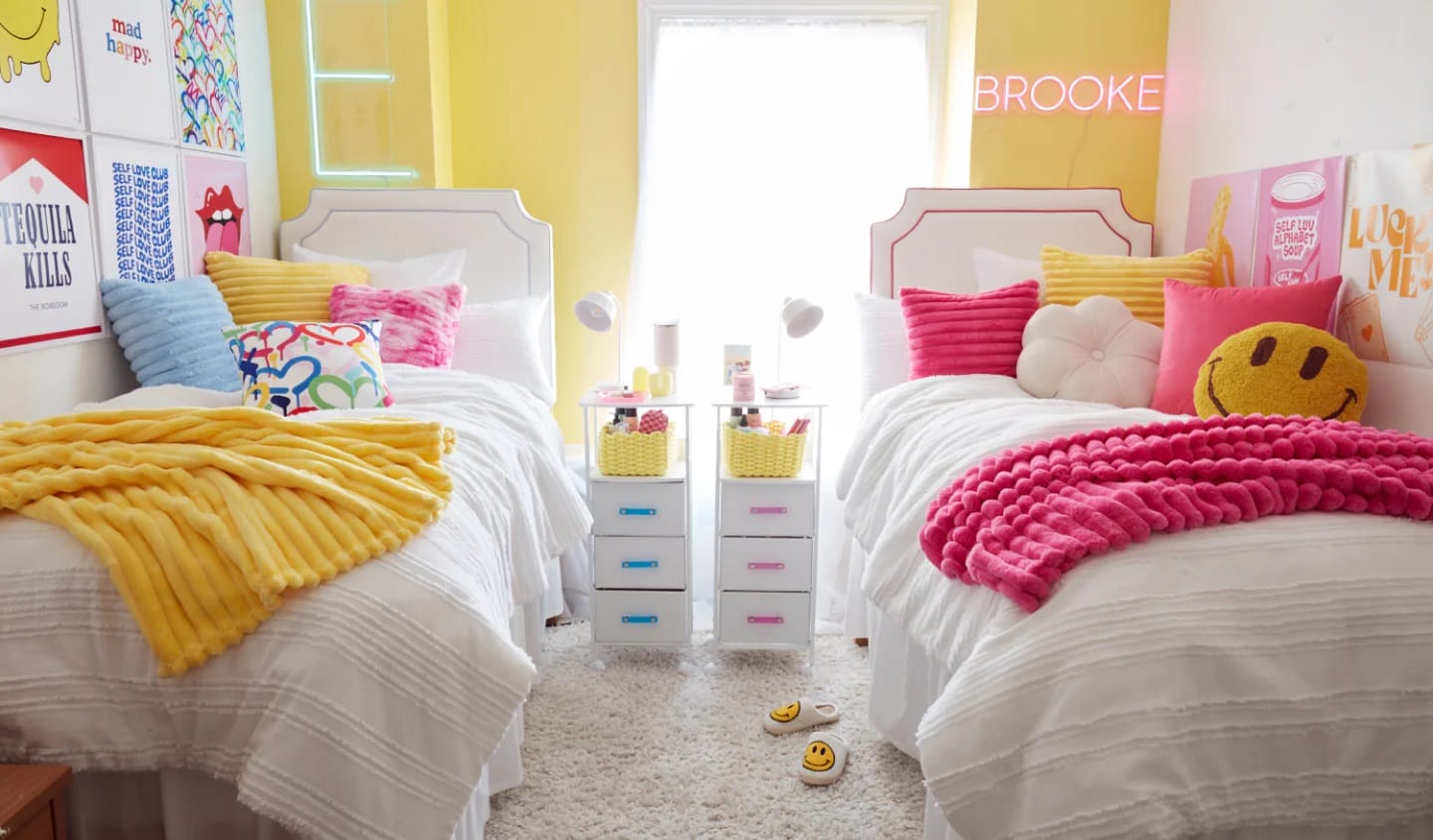 Bright room with twin beds, yellow and pink color scheme, colorful throw pillows, and playful decor.