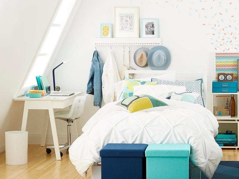 Bright and colorful dorm room with a study area, playful pillows, and storage ottomans.