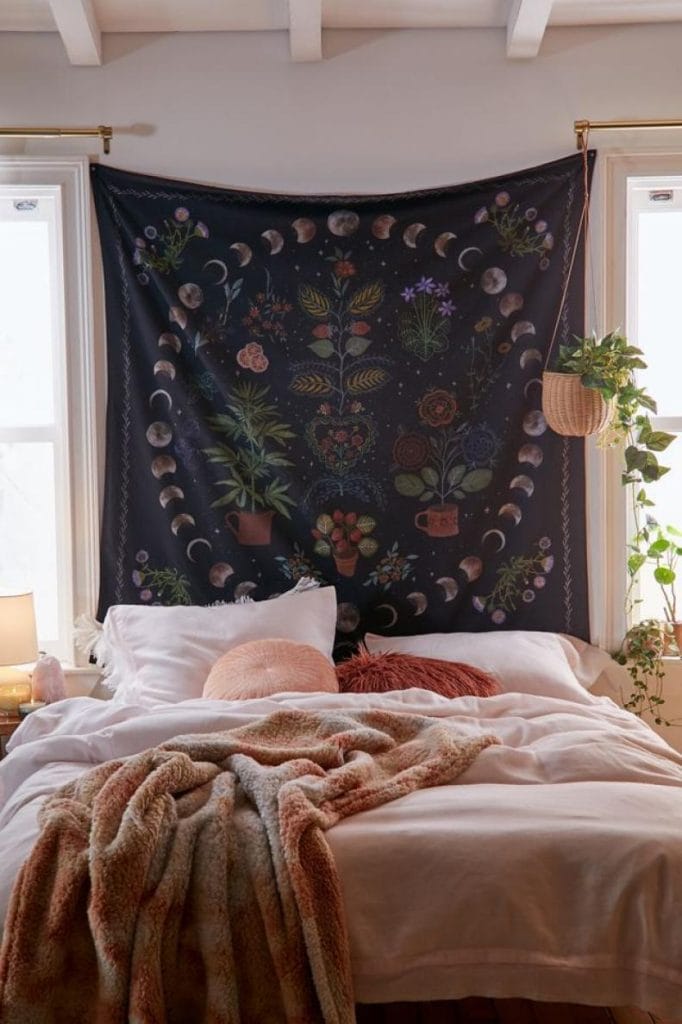 A dorm room with a celestial tapestry depicting moon phases and flowers, creating a mystical and serene atmosphere.