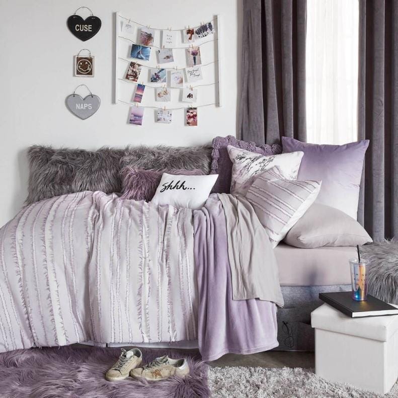 Dorm room with plush purple bedding and cozy decor.