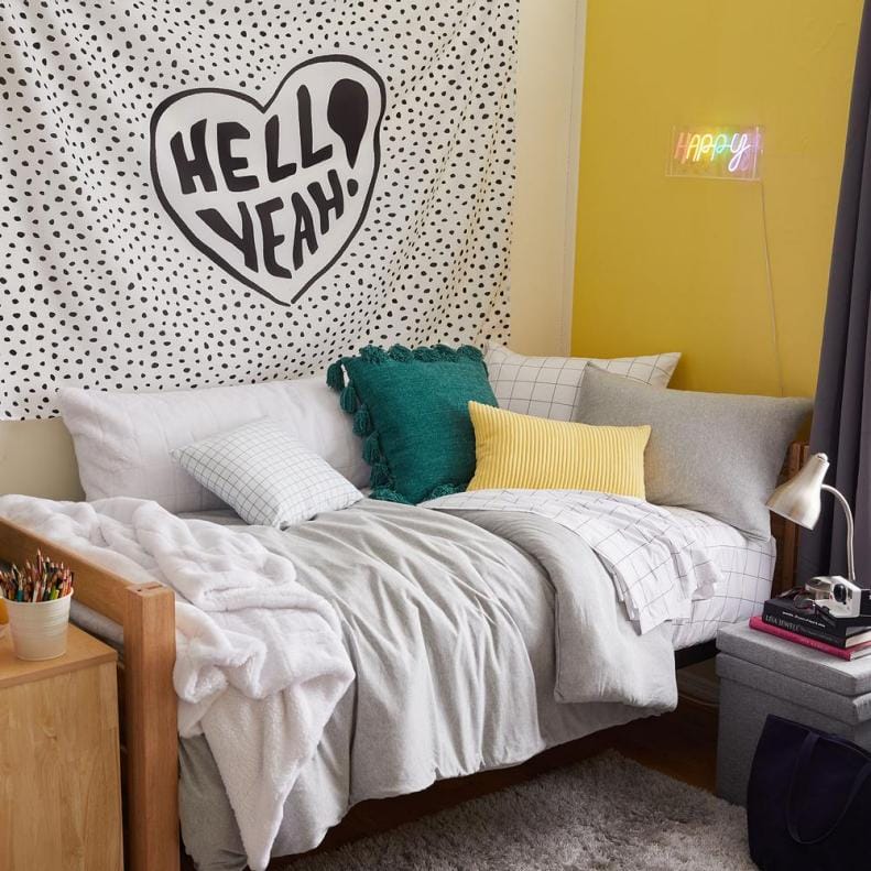 Dorm room with a polka dot tapestry and colorful pillows.