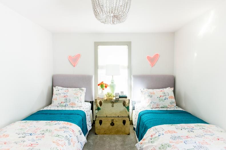 Twin dorm room with heart-shaped decor and bright bedding.