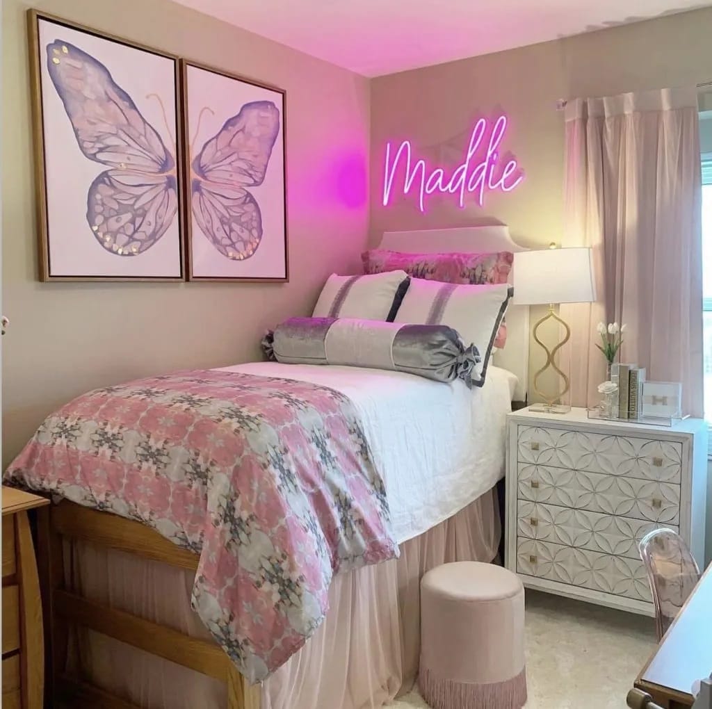 An elegant bedroom with personalized neon name sign, butterfly artwork, and pink and gray bedding.