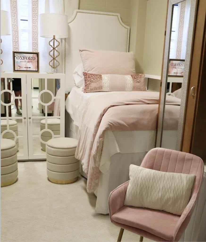 Bedroom with blush bedding, gold accents, and a stylish chair