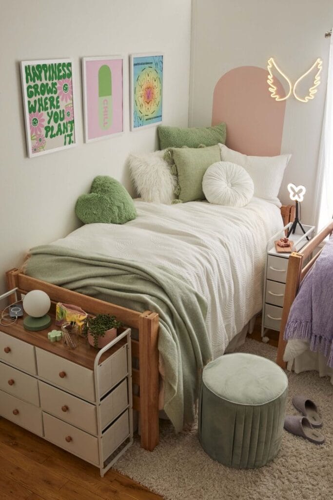 Bed with pastel green pillows and blankets, neon wing wall light, and cozy decor elements.