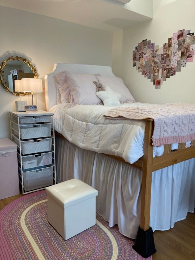 Bed with pink and white bedding, heart-shaped photo collage, and decorative mirror.