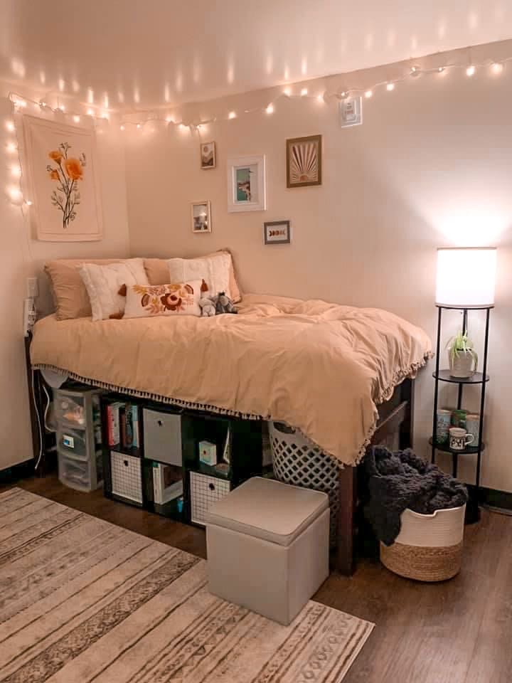 A warm dorm room with neutral bedding, string lights, functional storage, and minimalist wall decor.