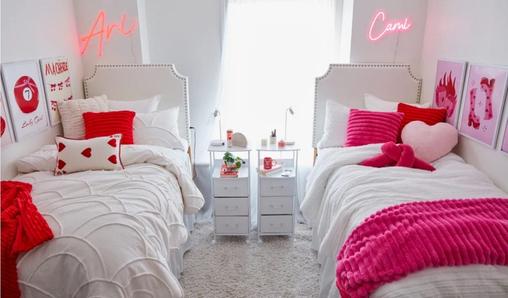 Room with a plush bed, pink and green pillows, and string lights.