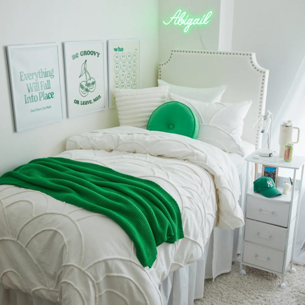 A bedroom with a neon sign, minimalist wall art, white bedding, and green accents.