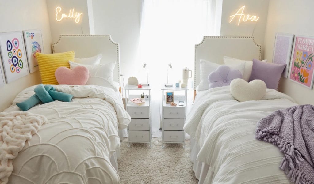 Two beds with neon name signs, colorful pillows, and bedside tables.