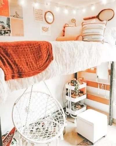 A bed with orange accents and a hanging chair, creating a boho chic design.