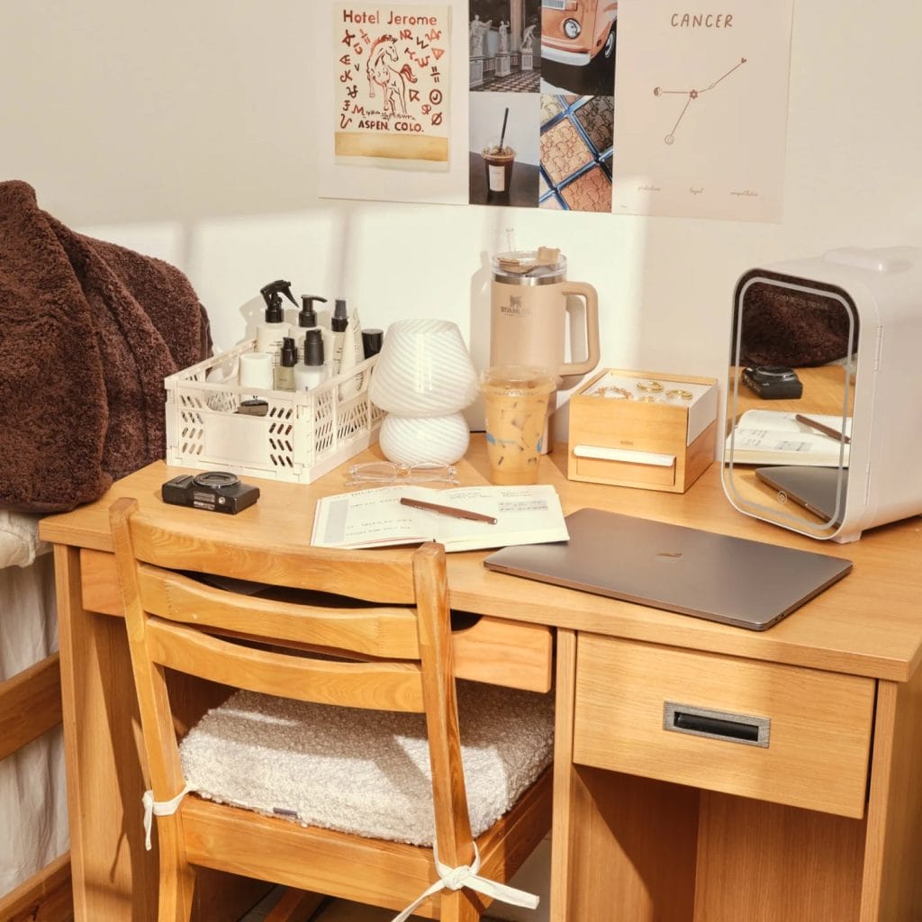 A neat study area with a wooden desk, laptop, essential supplies, and decorative items.