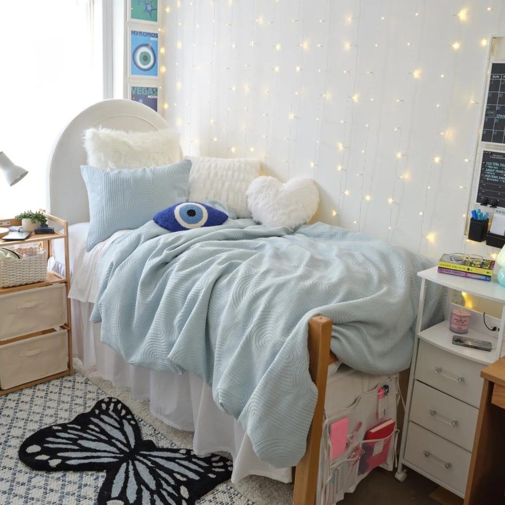 A cozy room with a white and blue bedspread, soft pillows, and string lights.