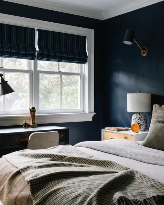 Teen boy's bedroom with navy blue walls, wooden furniture, and a cozy bed.