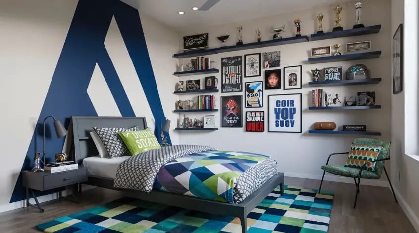 A teen boy’s room with bold graphic wall accents, colorful bedding, and shelves displaying trophies and artwork.