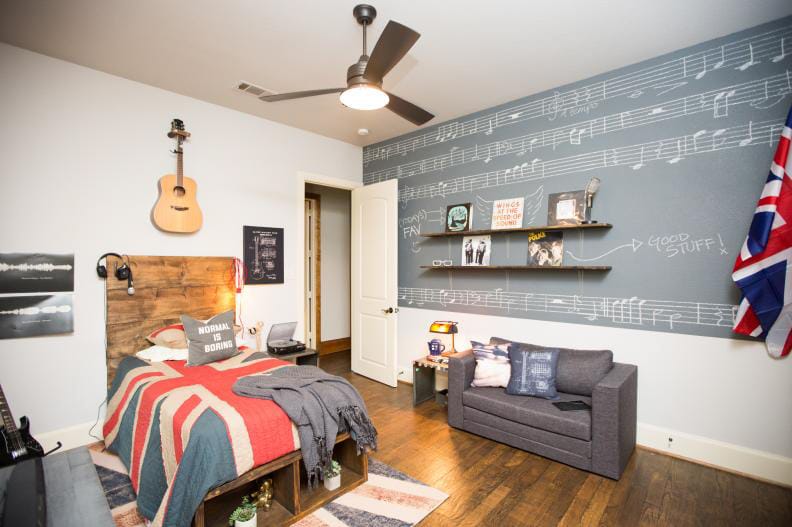 Teen boy's room with a music-themed chalkboard wall, wooden headboard, and guitar decor.