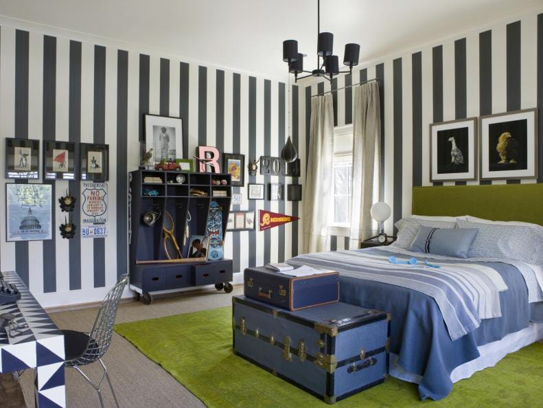 Teen boy's room with bold black and white striped walls, lime green headboard, and blue trunks.