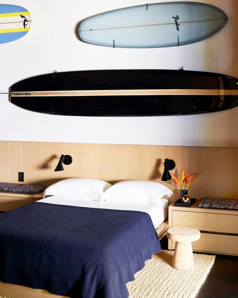 Teen boy's bedroom with a surfboard wall display, natural wood furniture, and minimalist decor.