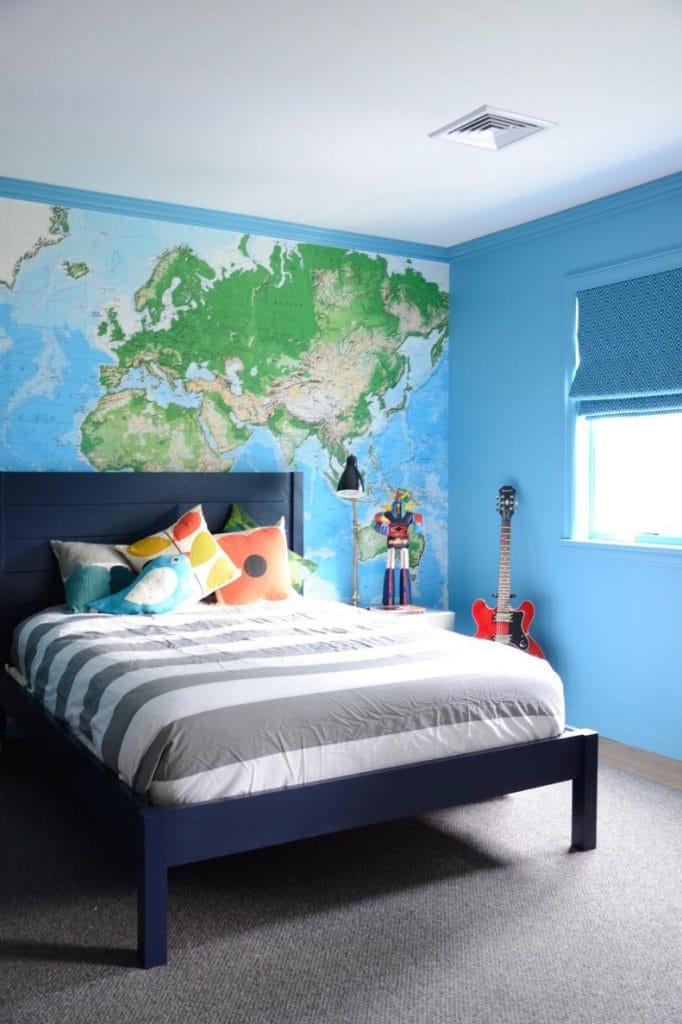 Teen boy's room with a world map mural, blue walls, and simple furniture.