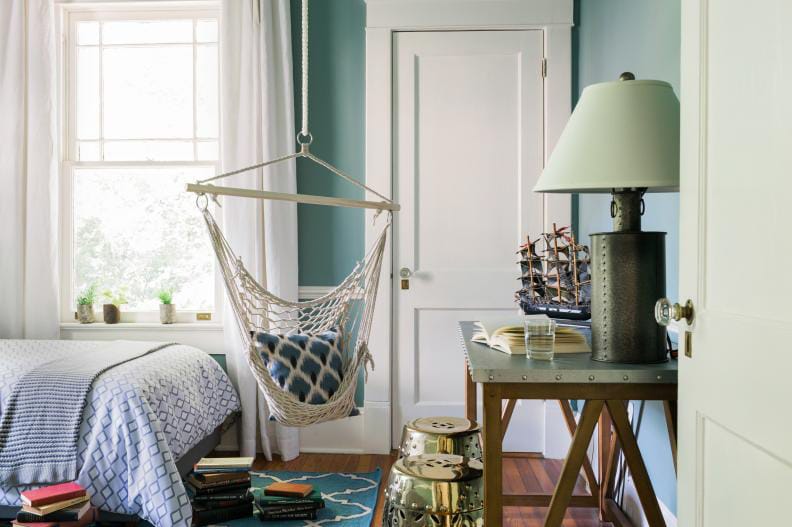 Teen boy's room with a hanging hammock chair, blue walls, and nautical decor.